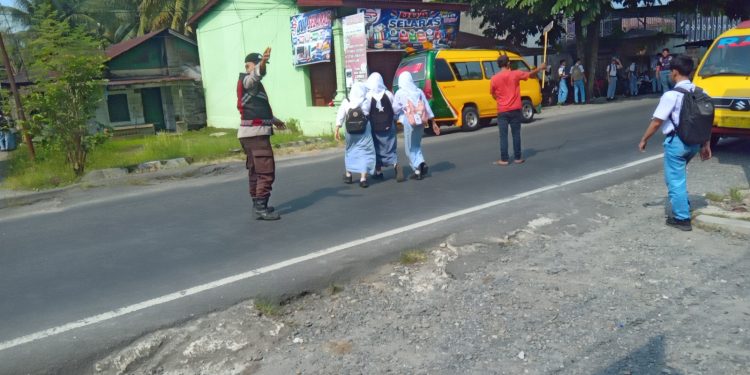 Jam Siang Padat, Bhabinkamtibmas Kuala Turun Atur Lalu Lintas di Depan Sekolah YPHB