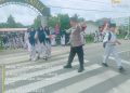 Bhabinkamtibmas Polsek Kuala Atur Lalu Lintas Siang Hari, Bantu Siswa Menyeberang dengan Aman